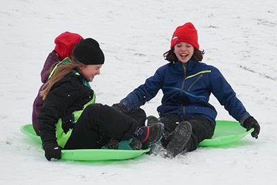 Two students sledding at school