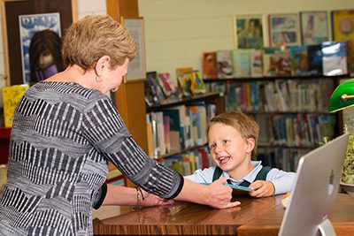 Librarian handing book to student