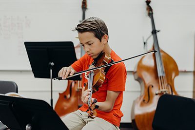 middle school student studies a sheet of music in orchestra