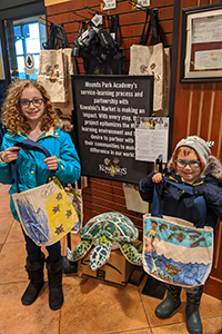 kindergarten student and fifth grader holding the bags they made together