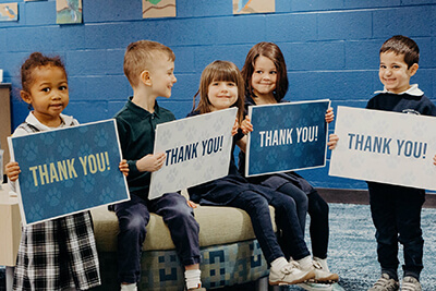 prep students in the library with thank you signs for alumni