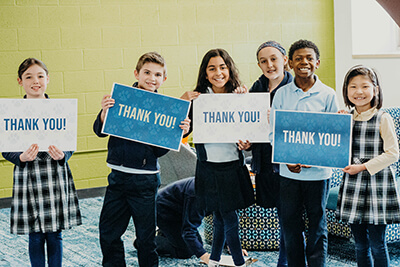 lower school students hold up thank you for alumni