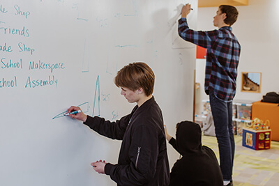 upper school students using makerspace whiteboard together