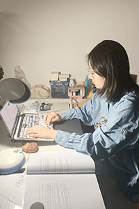 Ella Li seated at her desk working on her computer