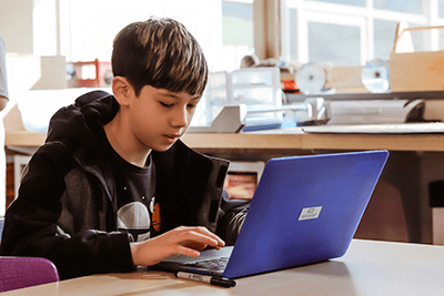 middle school student coding on laptop